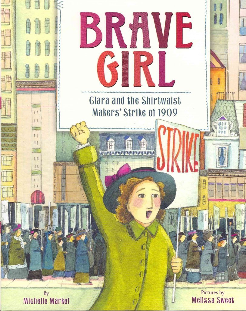 Book cover of Brave Girl: Clara And The Shirtwaist Makers’ Strike Of 1909 by Michelle Markel, Illustrated by Melissa Sweet, featuring a light-skinned woman with red curly hair with upraised fist holding a placard that reads "STRIKE" marching in a city.